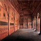 Jahangiri Mahal: A sequence of interconnected chambers, some embellished with plaster walls, leads to the riverside court of the Jahangiri Mahal, that was built between 1565 and 1569, in Fatehpur Sikri. It is defined by apartments on three sides, that on the west presents a triple-bayed, double-height entrance framed by slender stone columns that imitate timber originals. These features contrast with the arched recesses at either side and with the arched portals flanked by similarly-shaped recesses leading to the apartments on the north and south. A small octagonal pool set into the middle of the court is fed by a narrow water channel. The eastern perimeter of the court consists of a line of jalis (latticed screen) that permit views across the river. The walls (as seen from below) are adorned with polychrome panels set between octagonal towers with chhatris, as on the frontal facade of the pala.